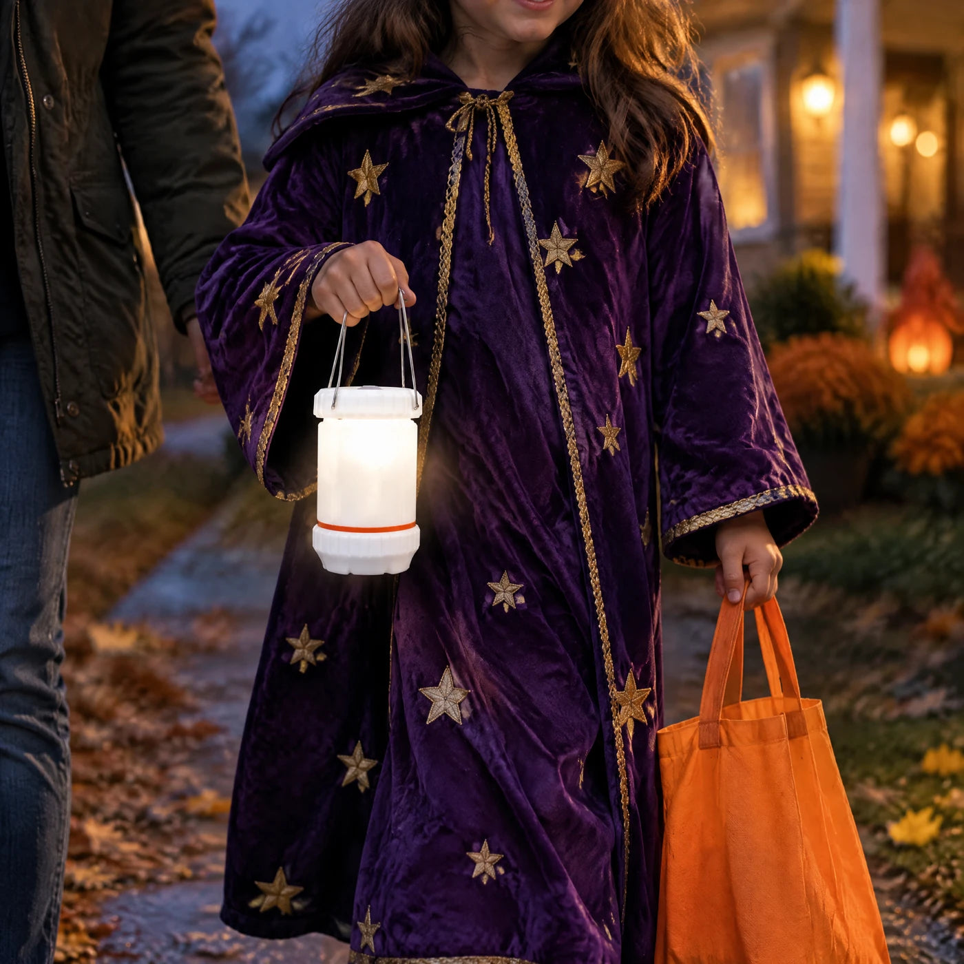 A child holding the lantern handle and a candy bag.